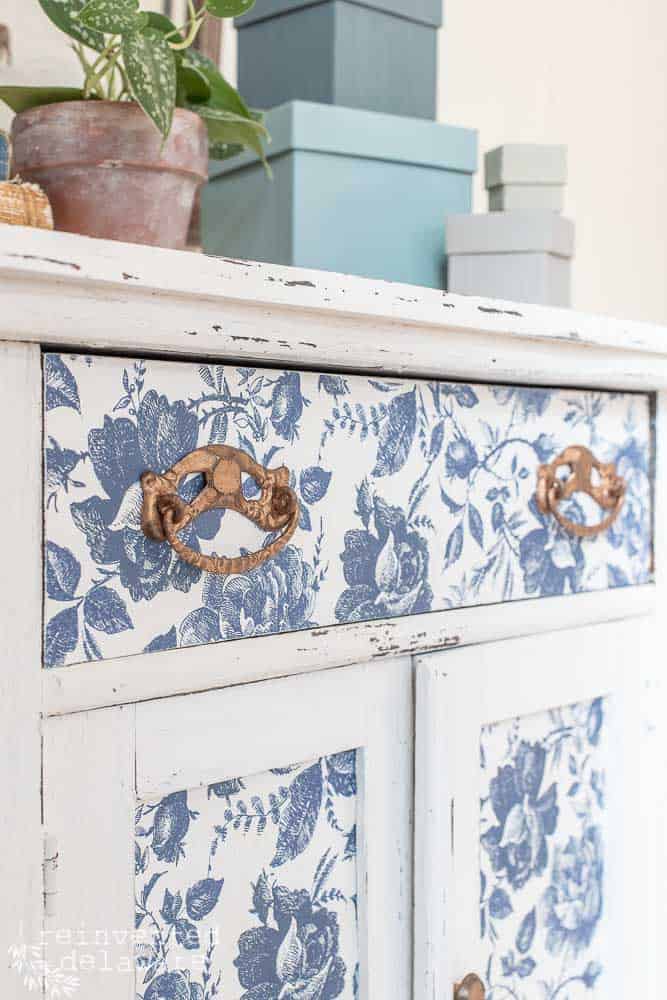 Close up of drawer pulls on a decoupaged piece of furniture.