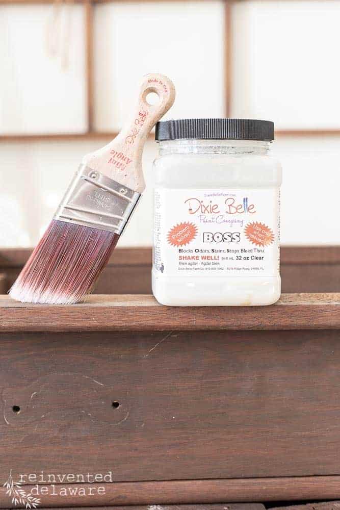 Closeup of Dixie Belle Boss and a paint brush sitting on top of an antique washstand.