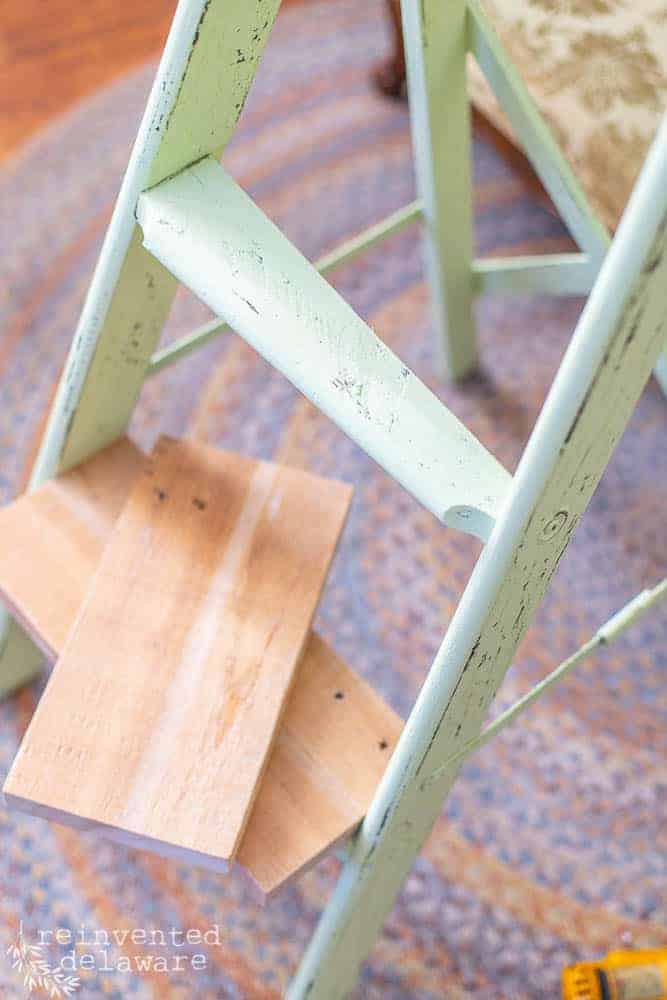 Close up of a broken step on an upcycled step ladder with the wood pieces that will be used to fix the wooden ladder.