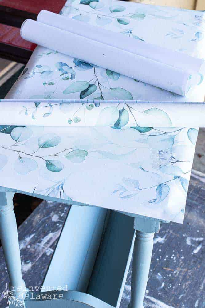 Peel and stick wallpaper laying on the top of an end table for a makeover idea.