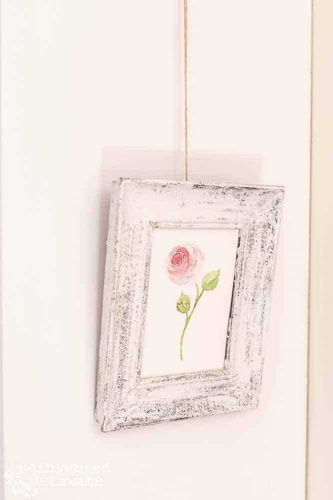 Small hand-painted watercolor artwork in a chippy painted frame. Watercolor painting of a rose.