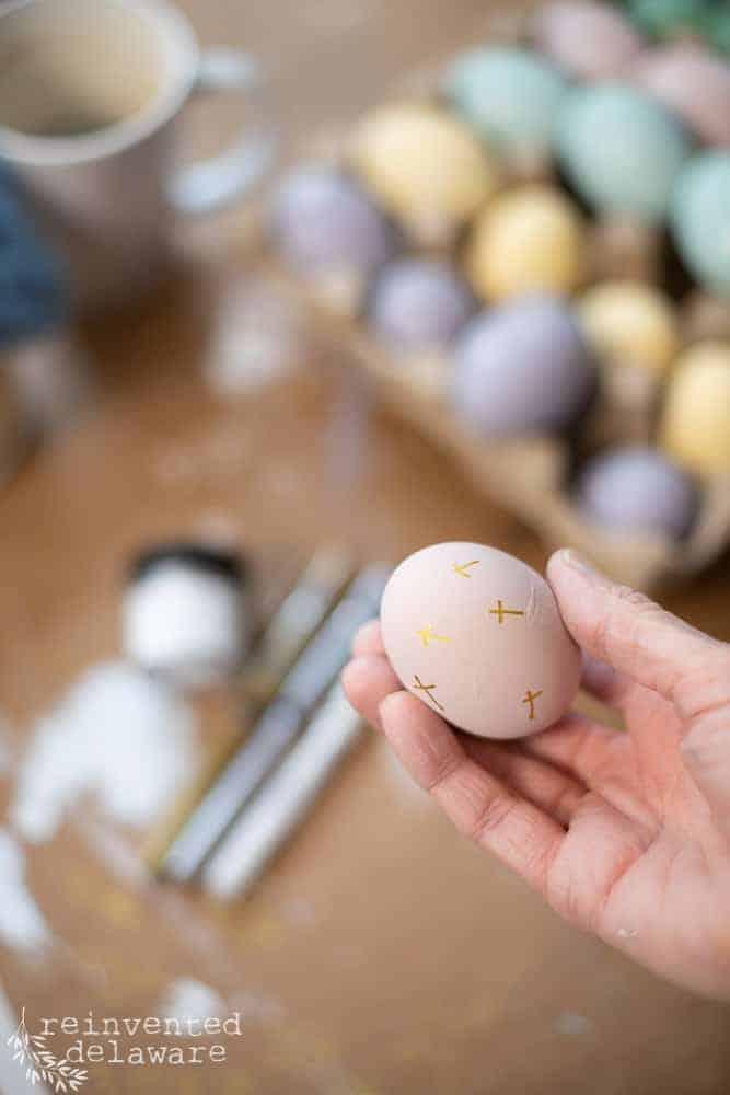 Lady holding an easy hand painted wooden egg with a cross drawn with a metallic marker.