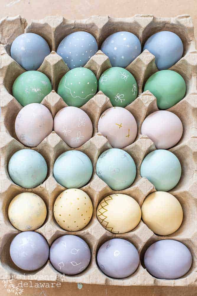 Hand painted wooden eggs in a carton container.