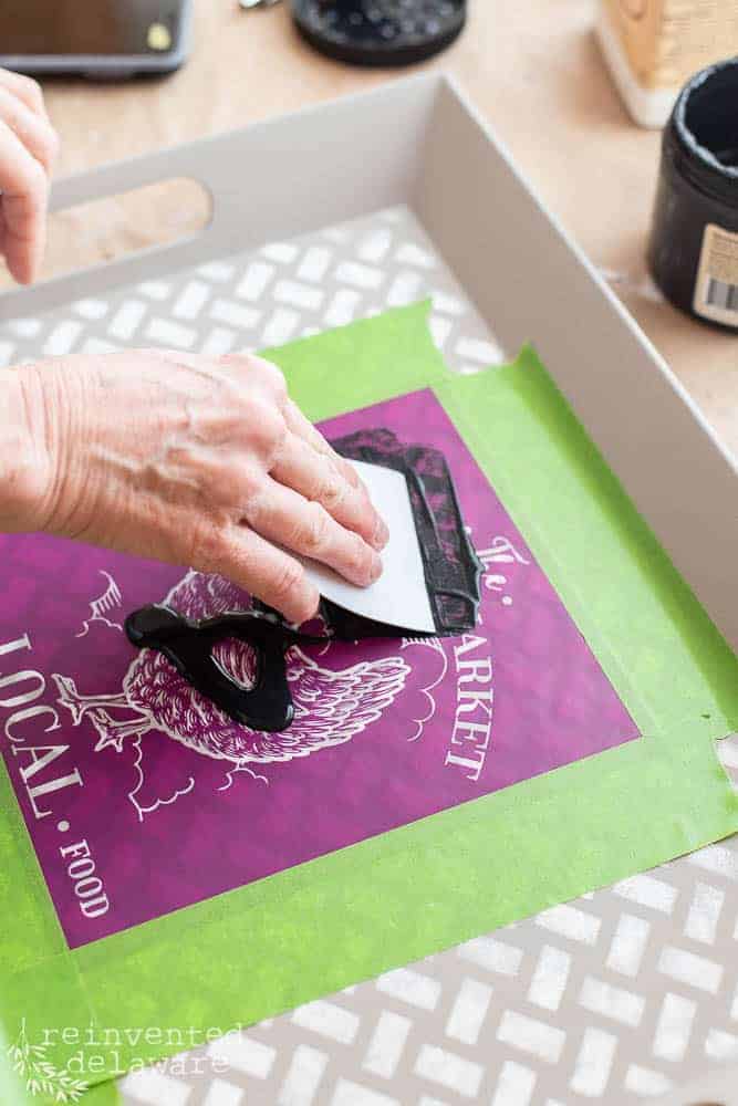 Lady applying paint to a silkscreen stencil design by Belles and Whistles.