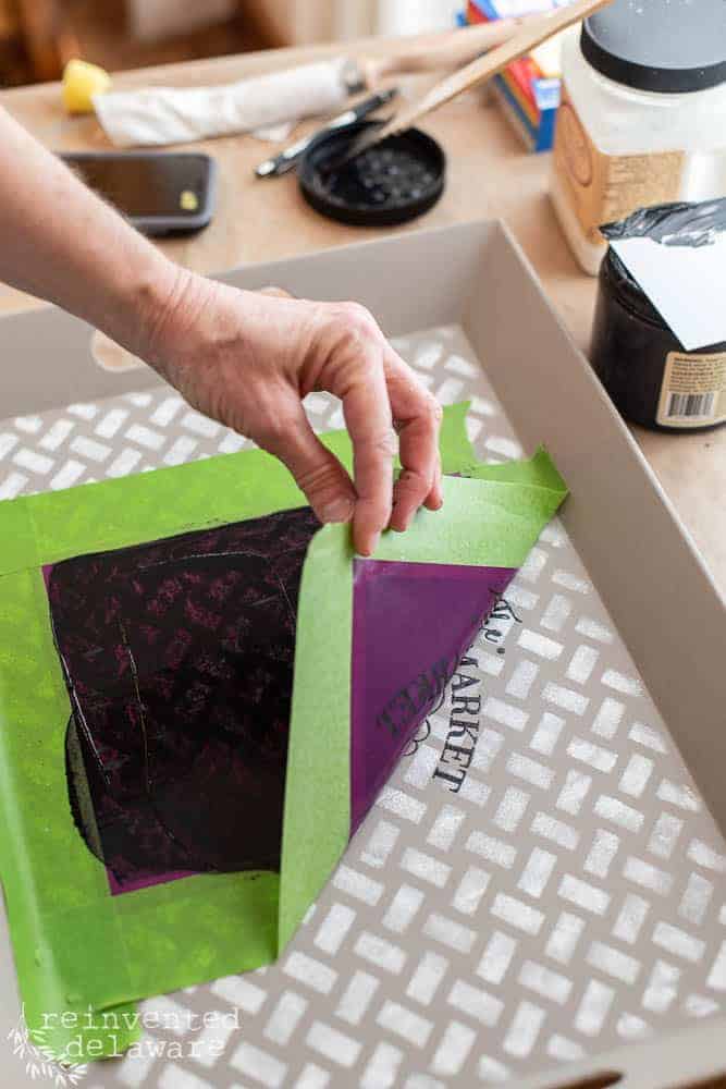 Lady removing silkscreen stencil from painted surface.