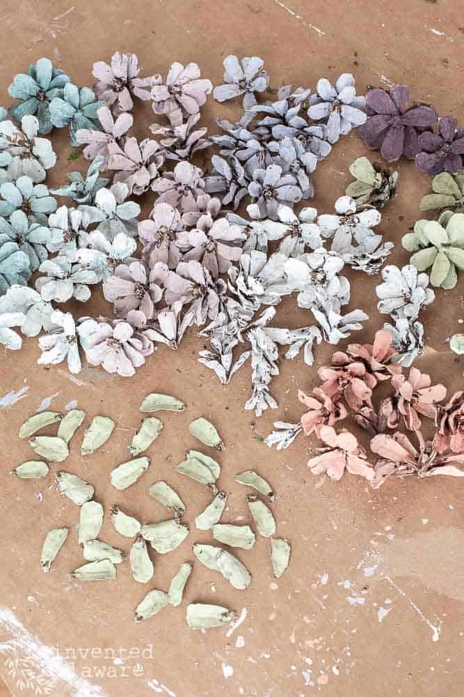 Pile of painted pine cone flowers in spring pastel colors for a pine cone table decoractions blog post.