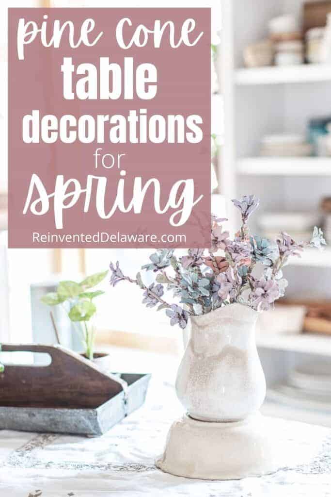 Pinterest graphic with text overlay "pine cone table decorations for spring" with an ironstone pitcher filled with pine cone flowers.