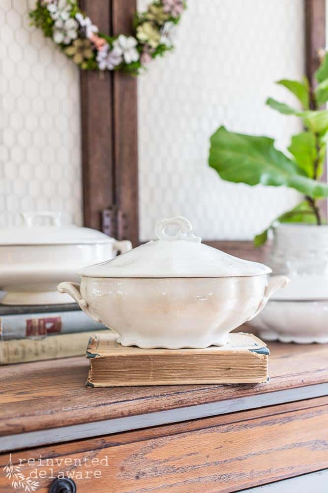 Close up of an antique ironstone soup tureen serving dish sitting on top of a vintage book.