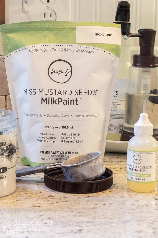 Bag of Miss Mustard Seed's Milk Paint, measuring cup and MilkMix EZ bottle on a kitchen counter.