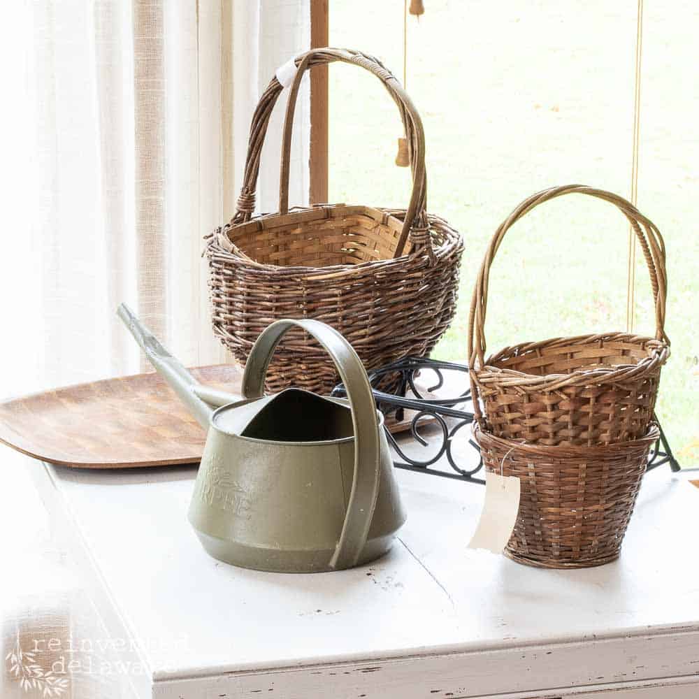 Thrift store items including baskets and a watering can ready for a trash to treasure ideas project.