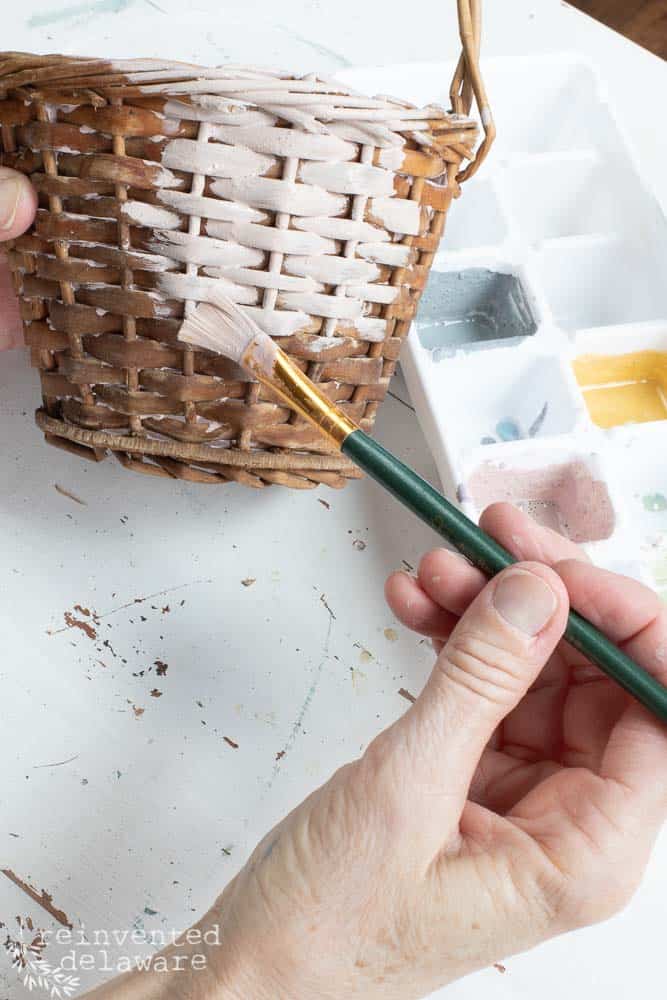 Lady painting a small thrift store basket for a trash to treasure ideas project.