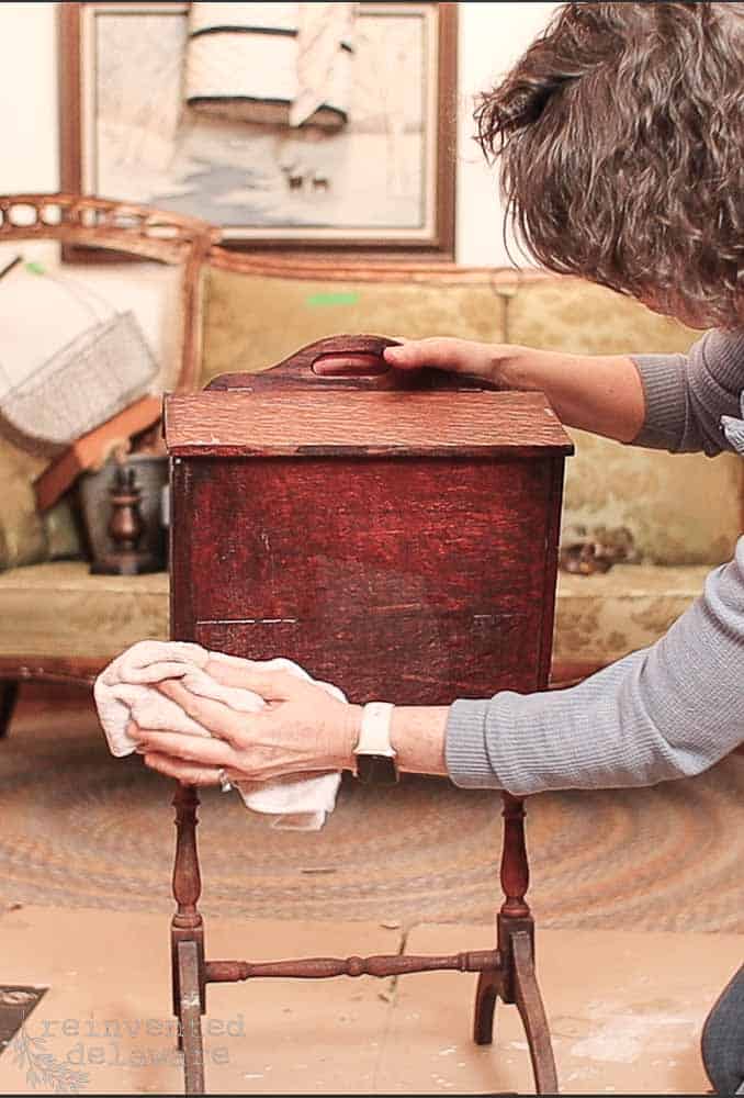 Lady cleaning an antique sewing box for a vintage makeover with milk paint.