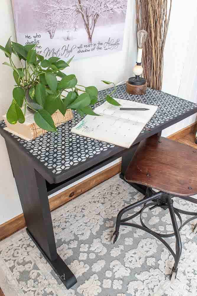 top of repurposed desk project that used chalk paint and a stencil staged with antique office chair, antique lamp and a bullet journal notebook