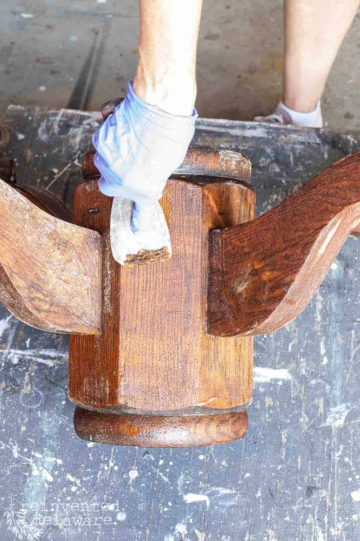 lady scrapping off old finish on an upcycled kitchen table