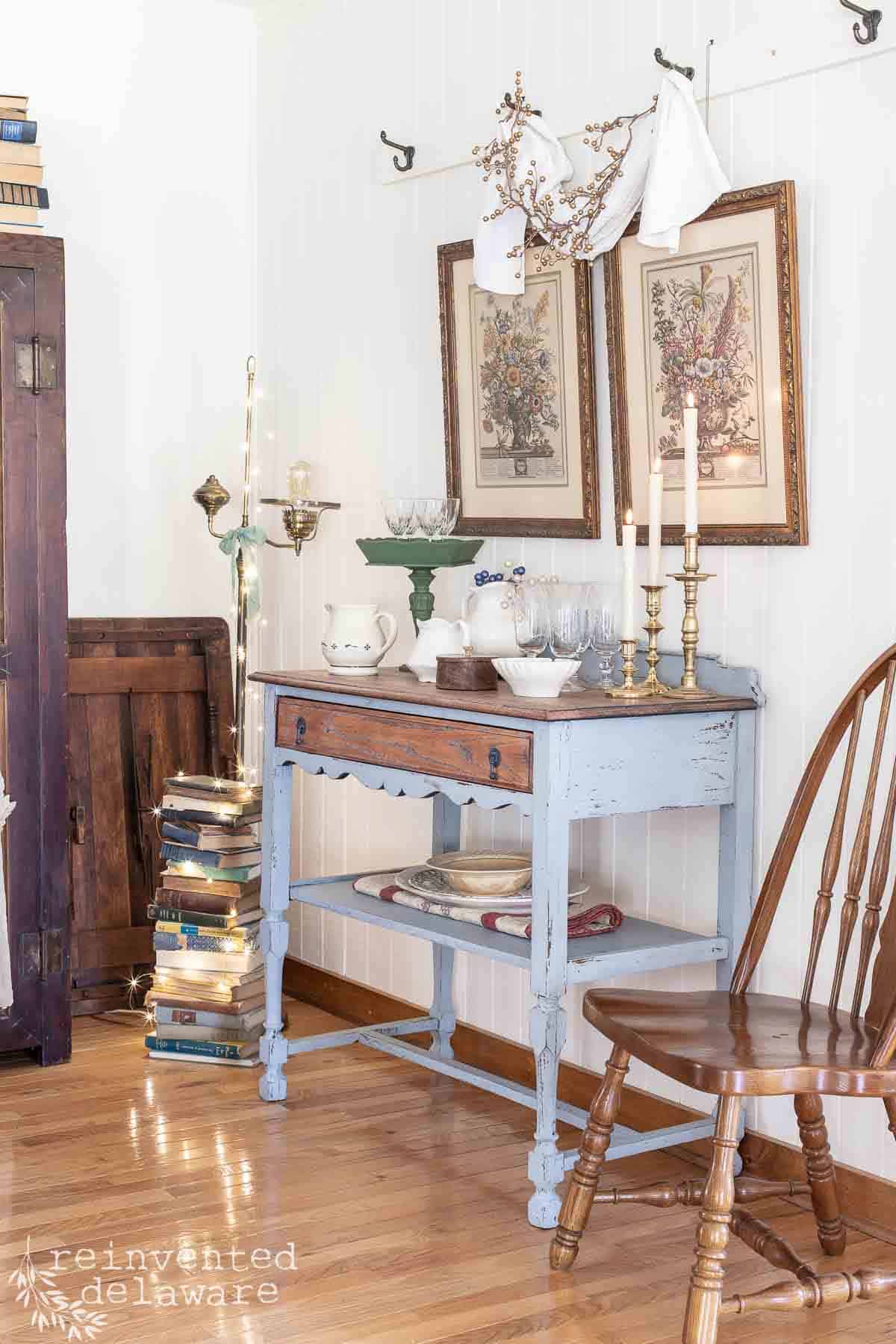 antique sideboard with vintage dishes displayed on top and vintage decor pieces including brass candlesticks for a simple vintage inspired Christmas Home Tour