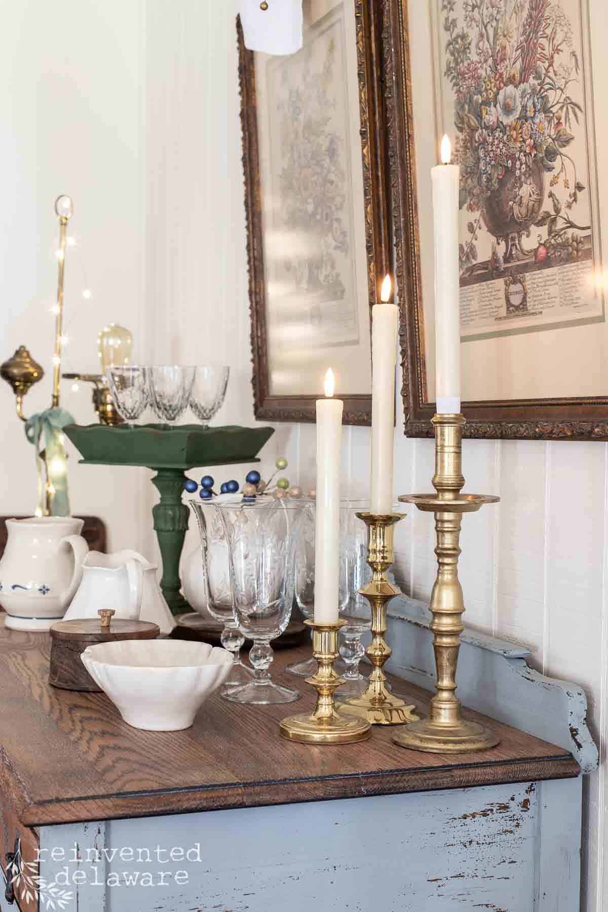 vintage brass candlesticks on top of an antique buffet table