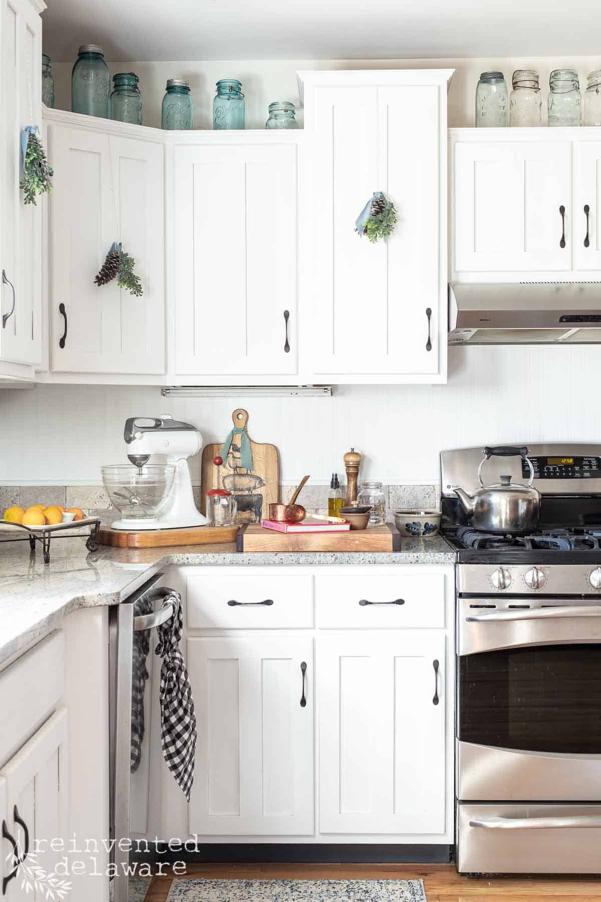 white painted kitchen cabinets with pine cone ornaments on the door for handmade Christmas decor