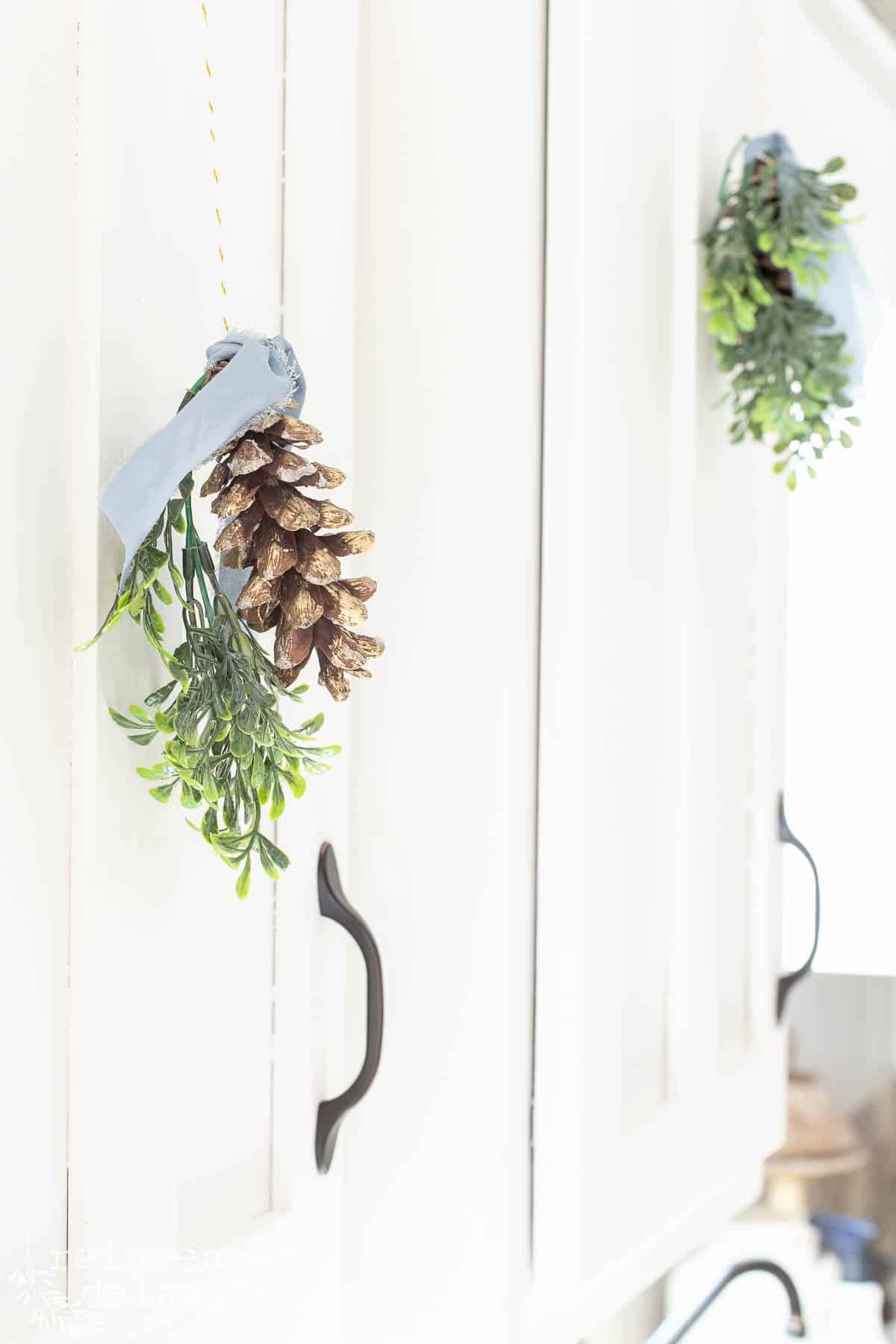 pine cone ornaments hanging on kitchen cabinets as Christmas decorating ideas
