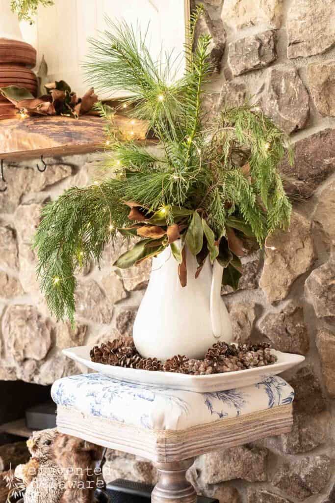 antique ironstone pitcher filled with fresh greenery and sitting on a vintage ironstone platter