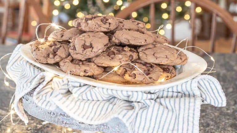 A white plate piled with chocolate chip cookies made from cake mix rests on a blue and white striped cloth. Delicate string lights adorn the plate, casting a glowing, festive background.