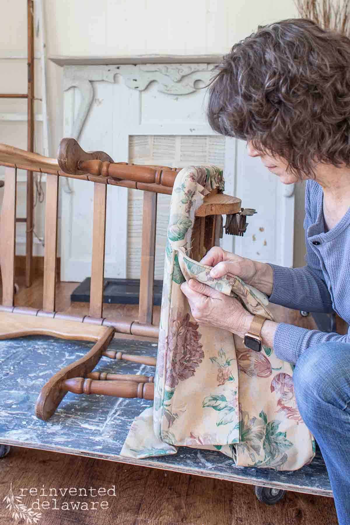 lady removing outdated fabric on rocking chair DIY project