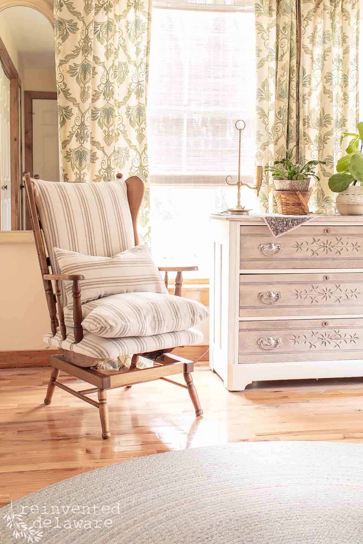 reupholstered rocking chair in a bedroom with vintage dresser