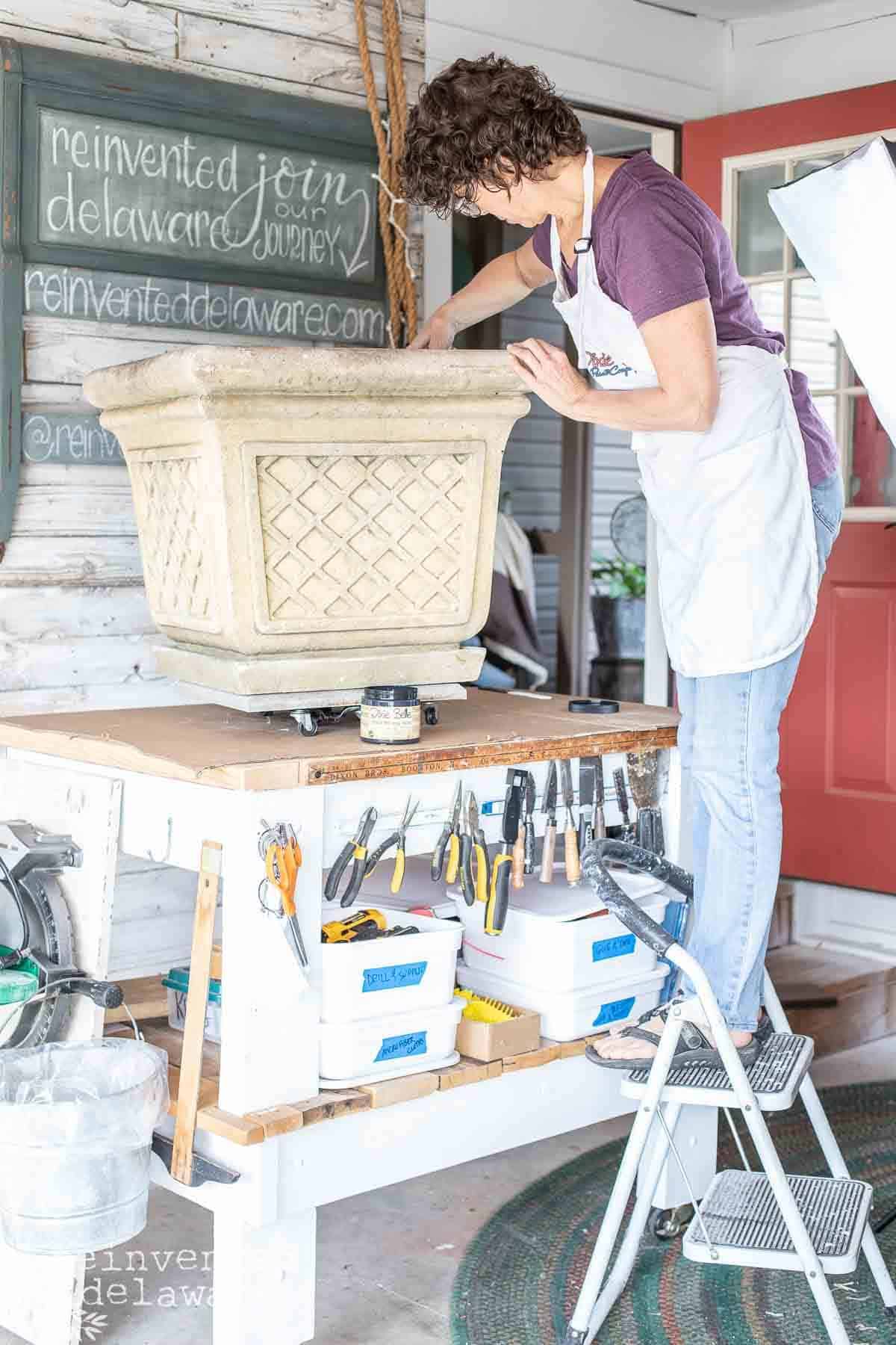 lady painting a thrift store planter for an outdoor patio