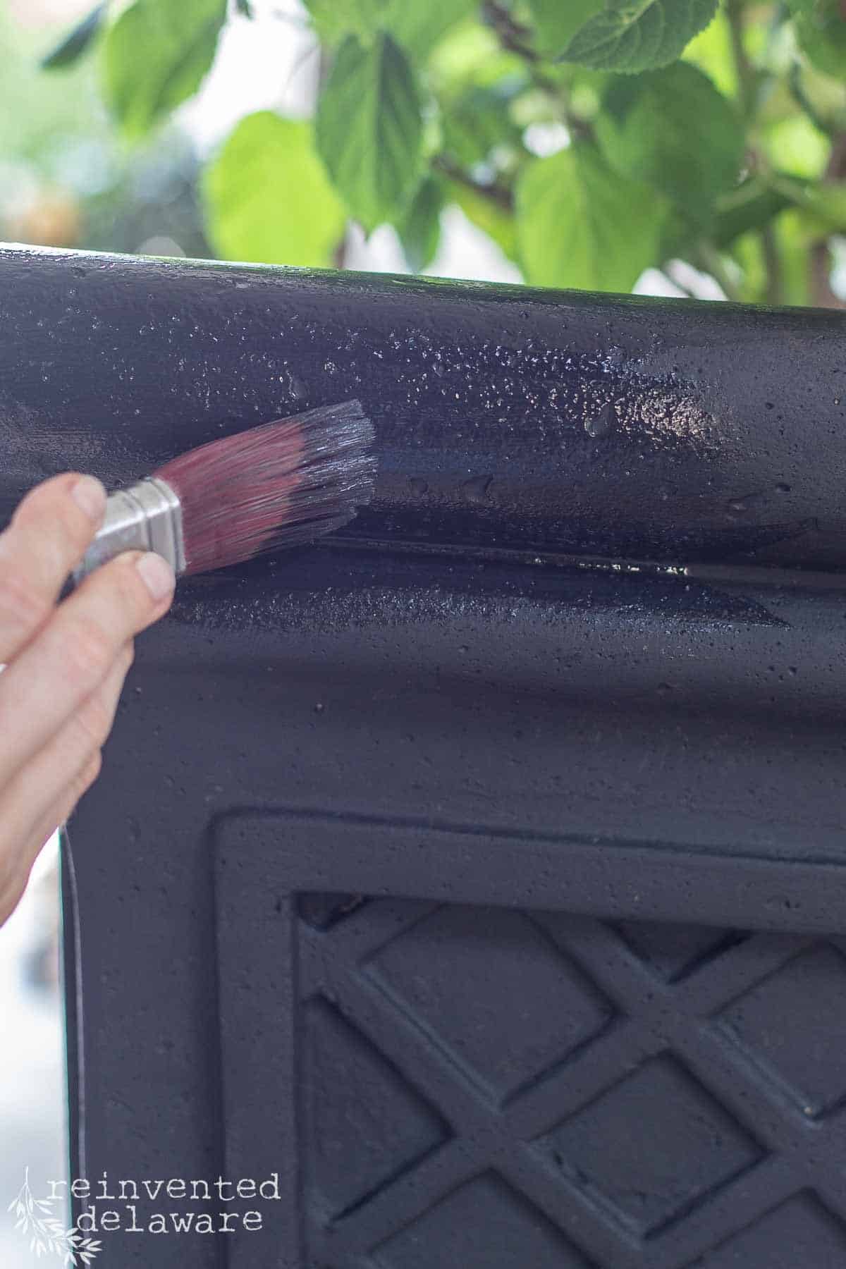 lady painting an upcycled planter for an outdoor space on a patio