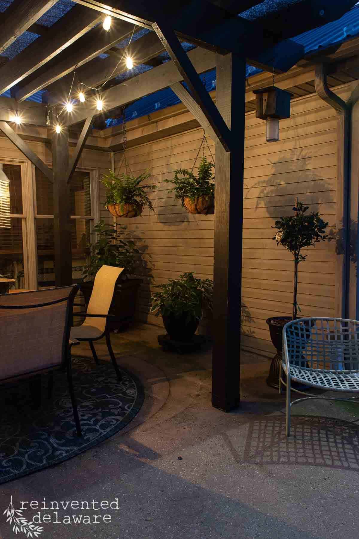 night scene on a backyard patio with lights and upcycled planters