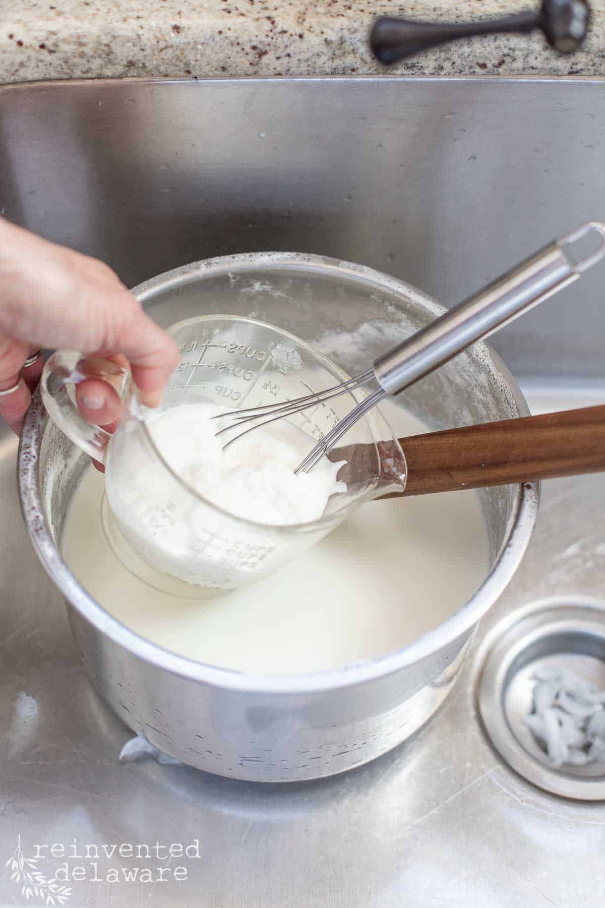 mixing yogurt starter into warm milk for homemade yogurt
