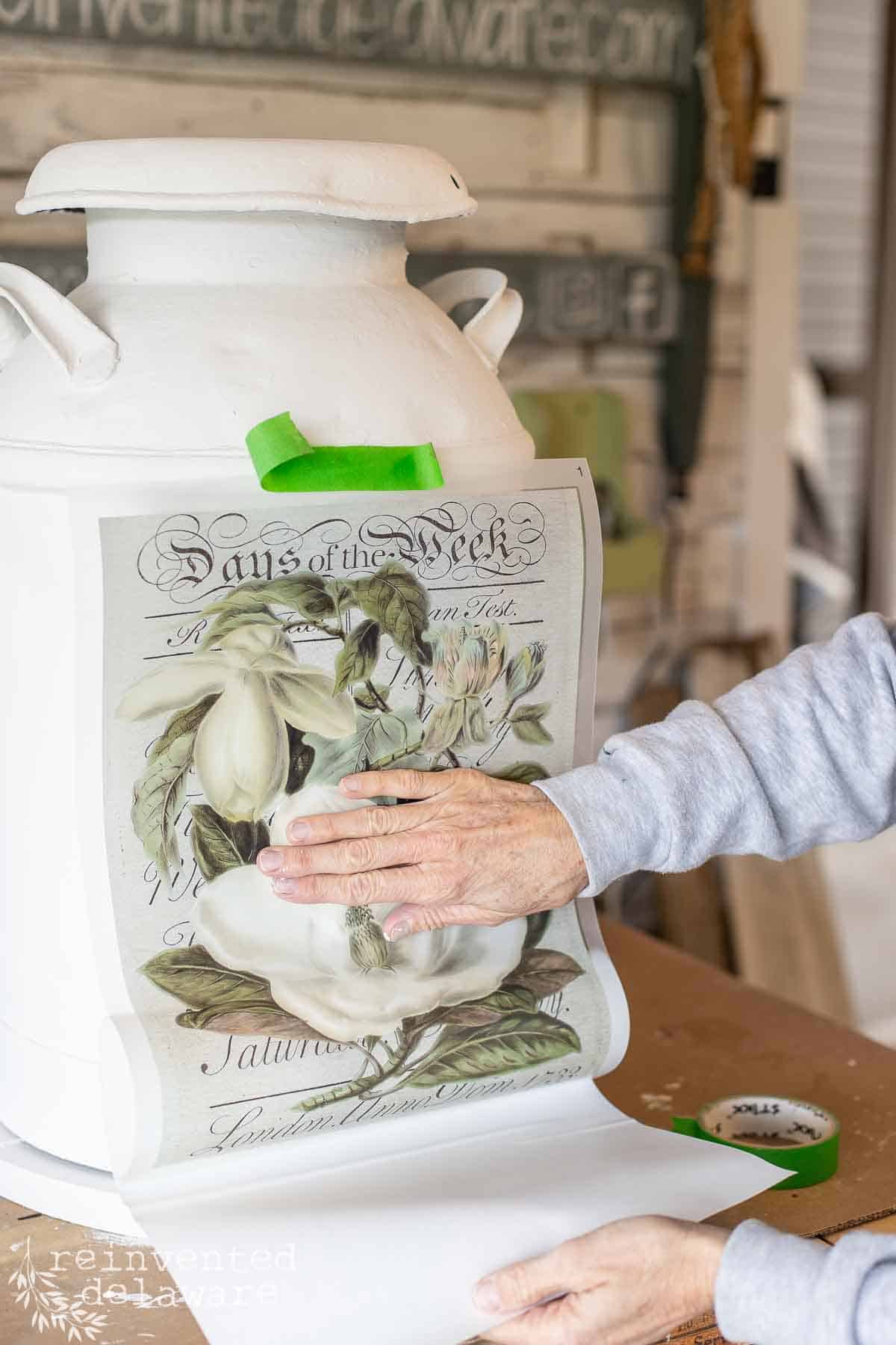 lady applying a transfer on upcycled vintage milk can