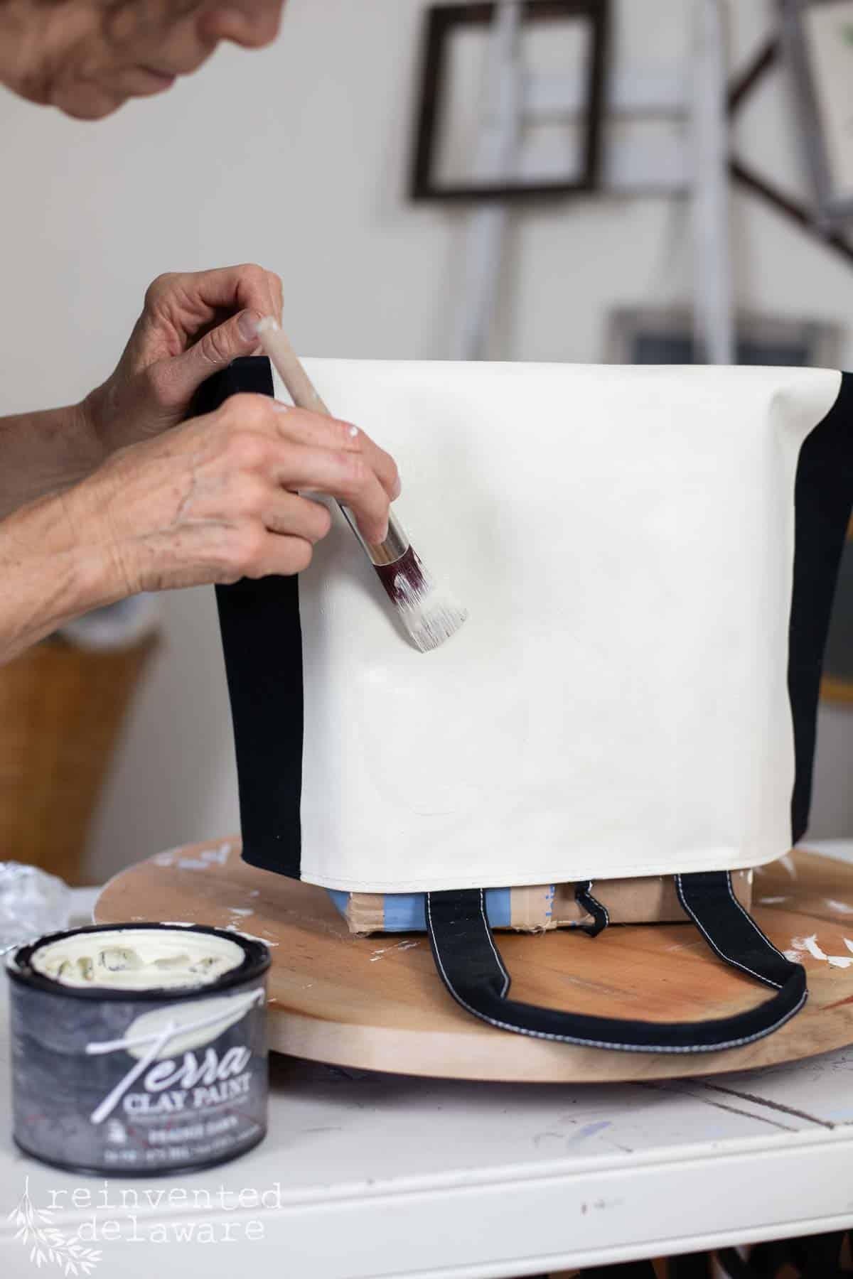 lady painting a heavy canvas bag from a thrift store