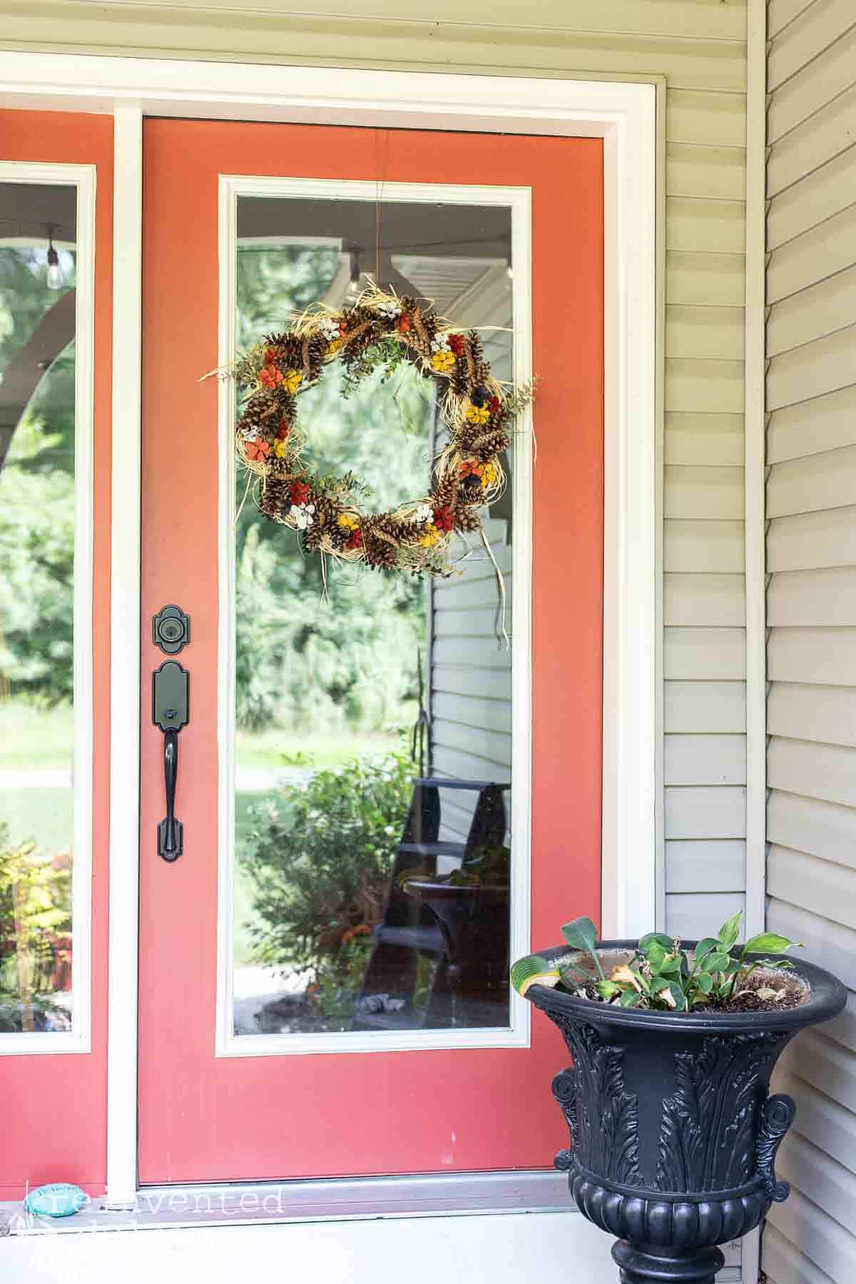 beautiful wreath for fall hanging on a front door made with pinecones
