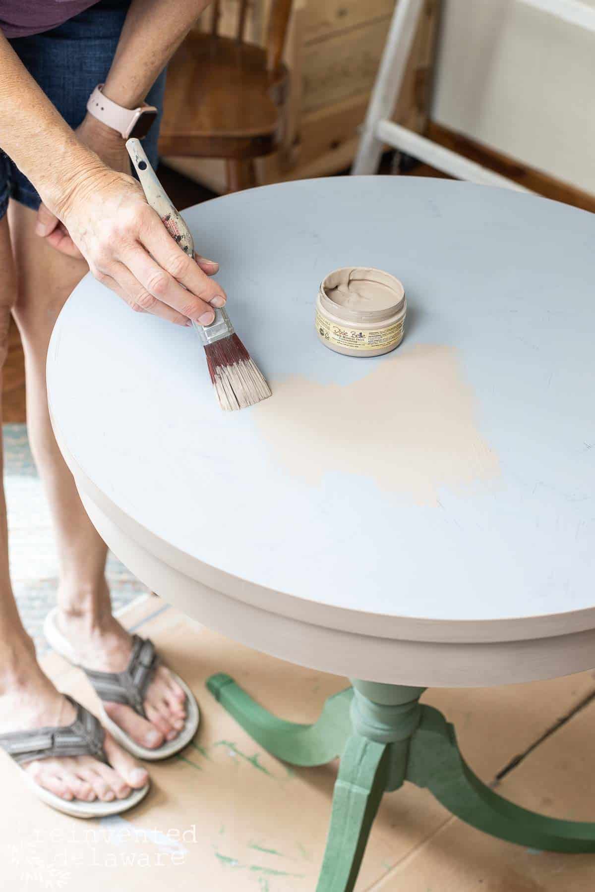 lady appyling chalk paint on the top of a Duncan Phyfe side table