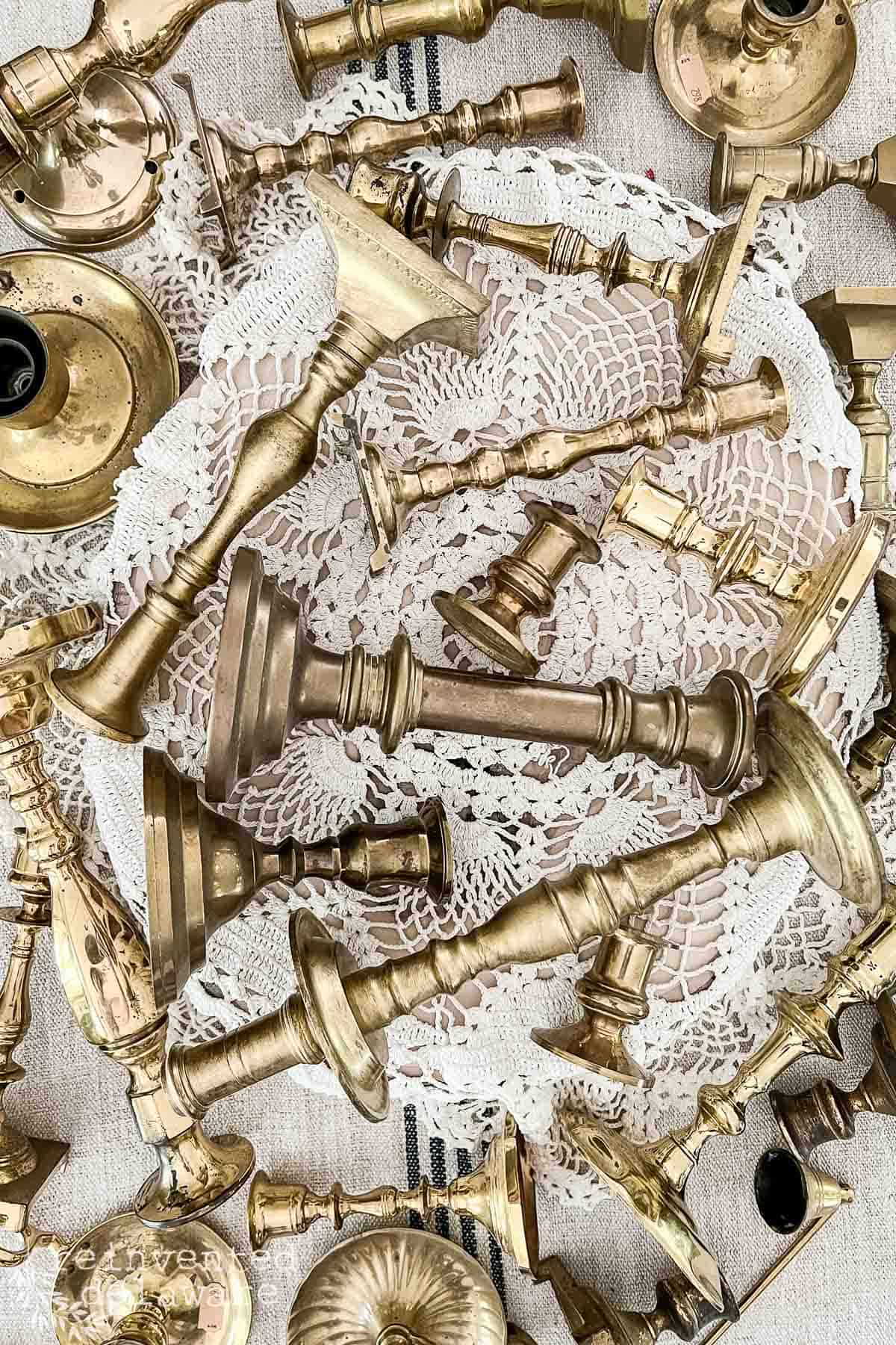 grouping of real brass candlesticks in a flat layout on a vintage doily