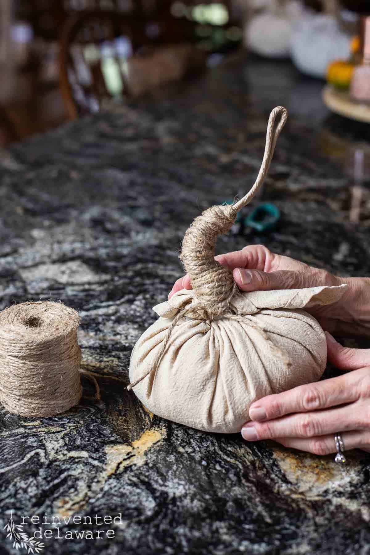 lady using jute twine to make a pumpkin stem on a craft