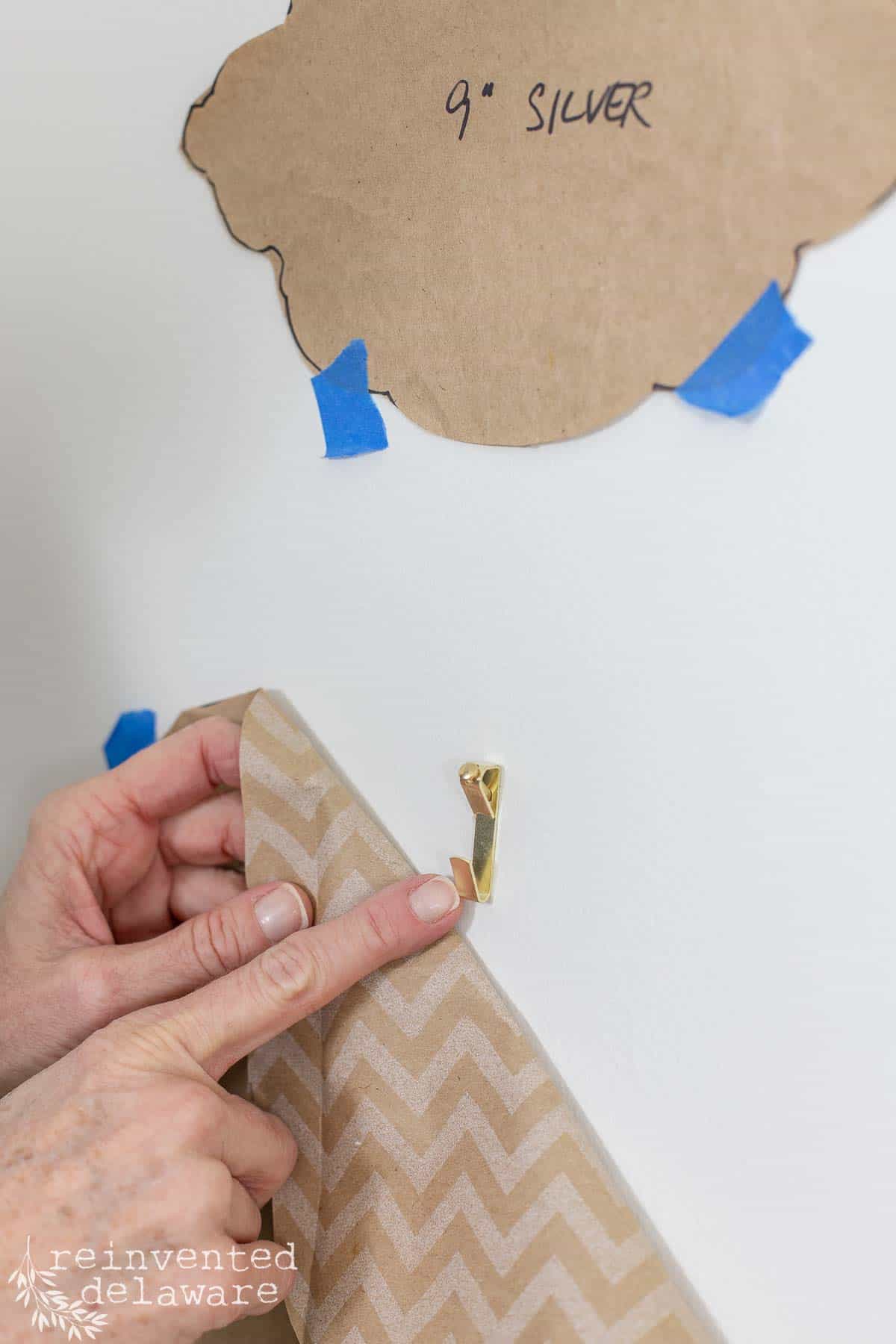 lady showing picture hanger on wall