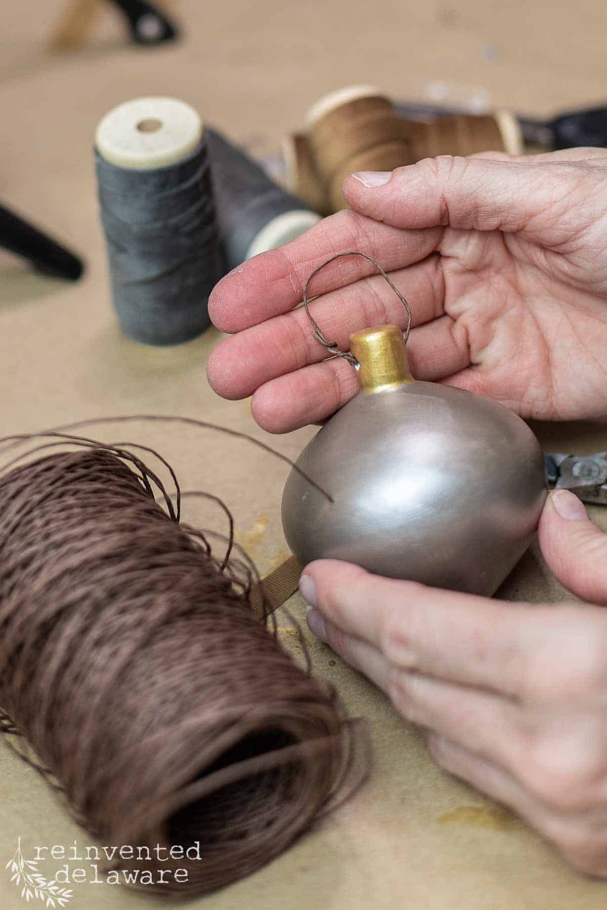 lady showing how to attach wire hanger to DIY homemade ornaments