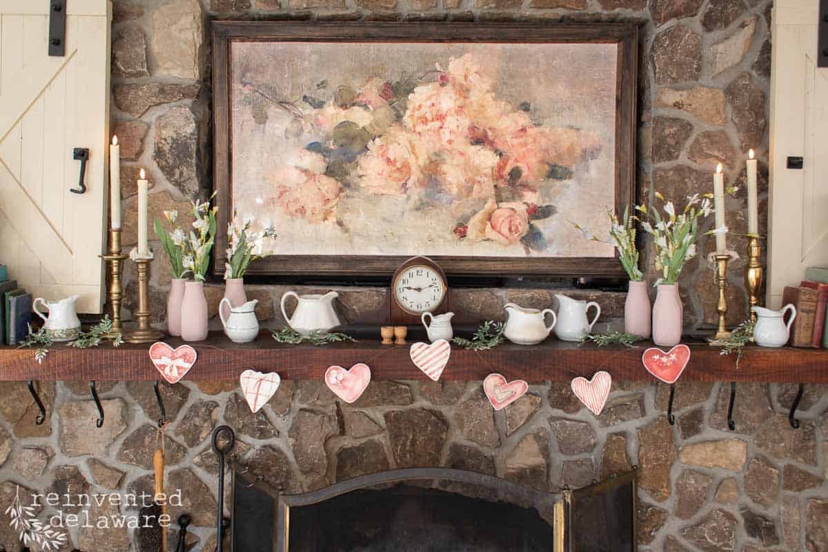 smart tv with vintage inspired art over a fireplace mantle with printable heart garland