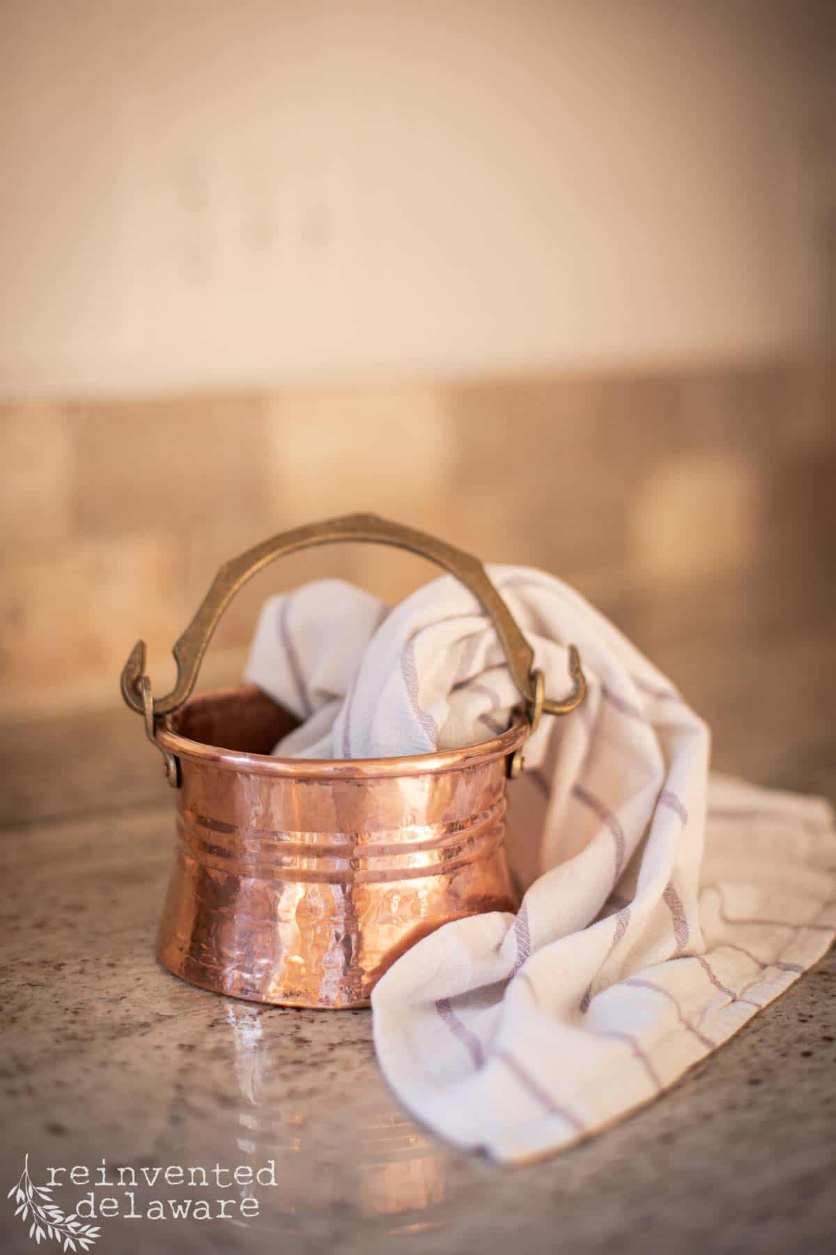 small copper cauldren or copper pot with a handle that has been cleaned with copper cleaner