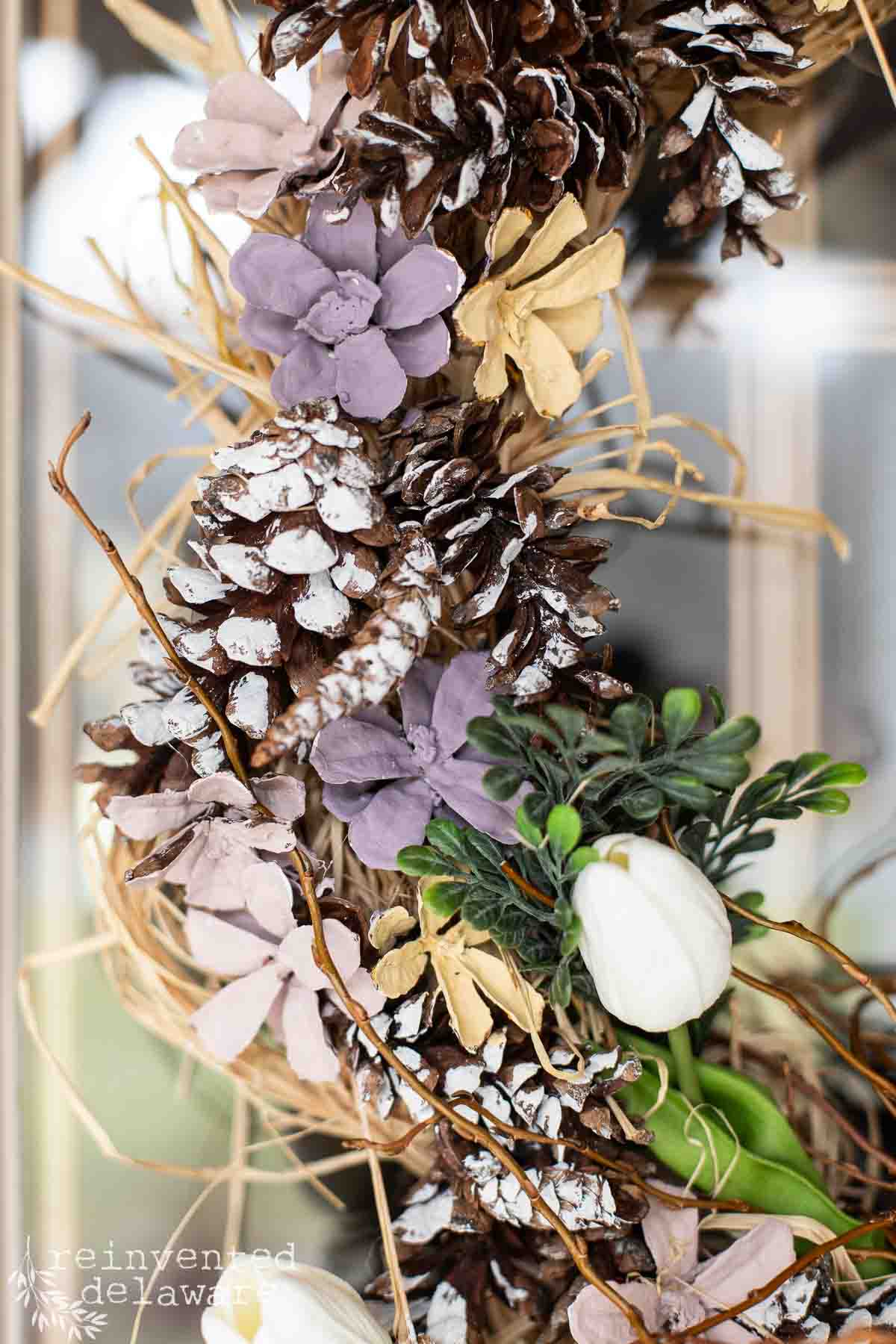 close up of diy wreath detail showing painted pine cone flowers and a faux tulip