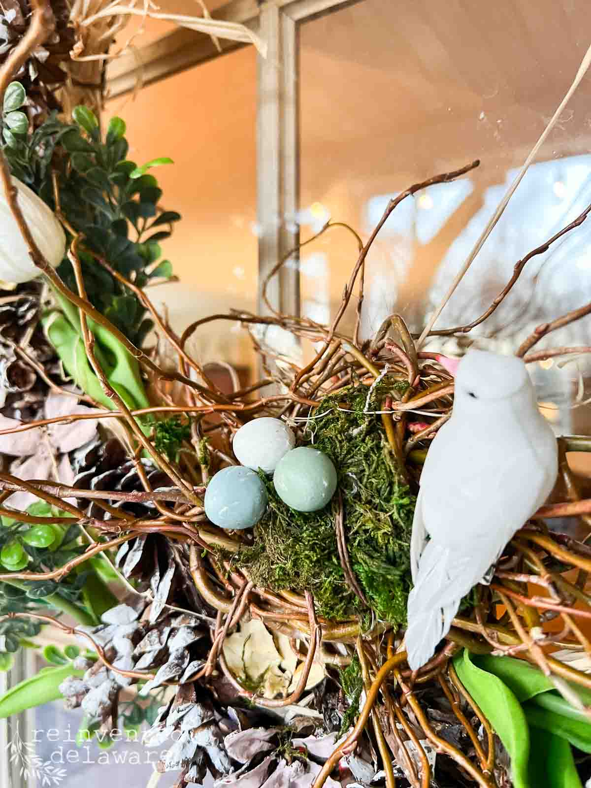 close up of faux bird's nest, faux bird and diy air dry clay eggs paintedin pastel colors for a DIY Easter Wreath