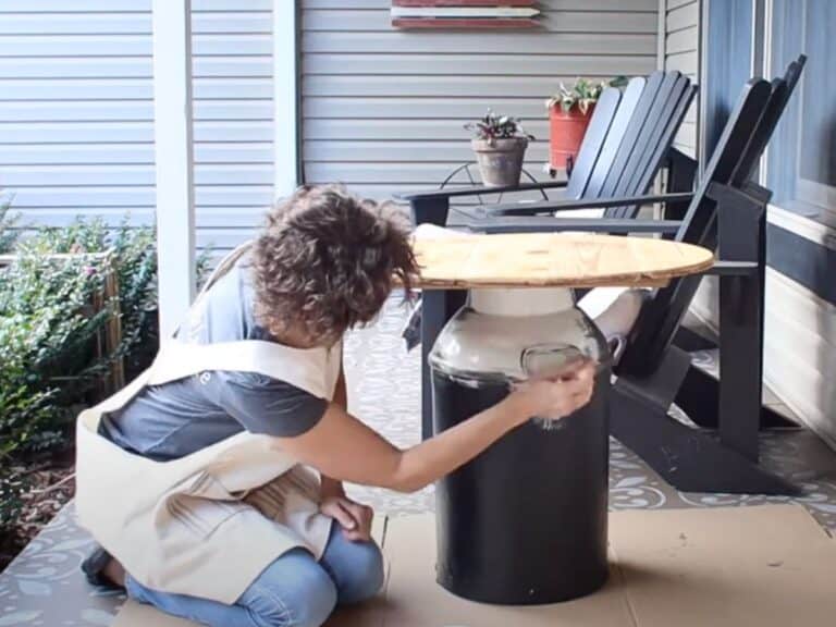 lady painting an old milk can using white chalk paint to make an upcycled table