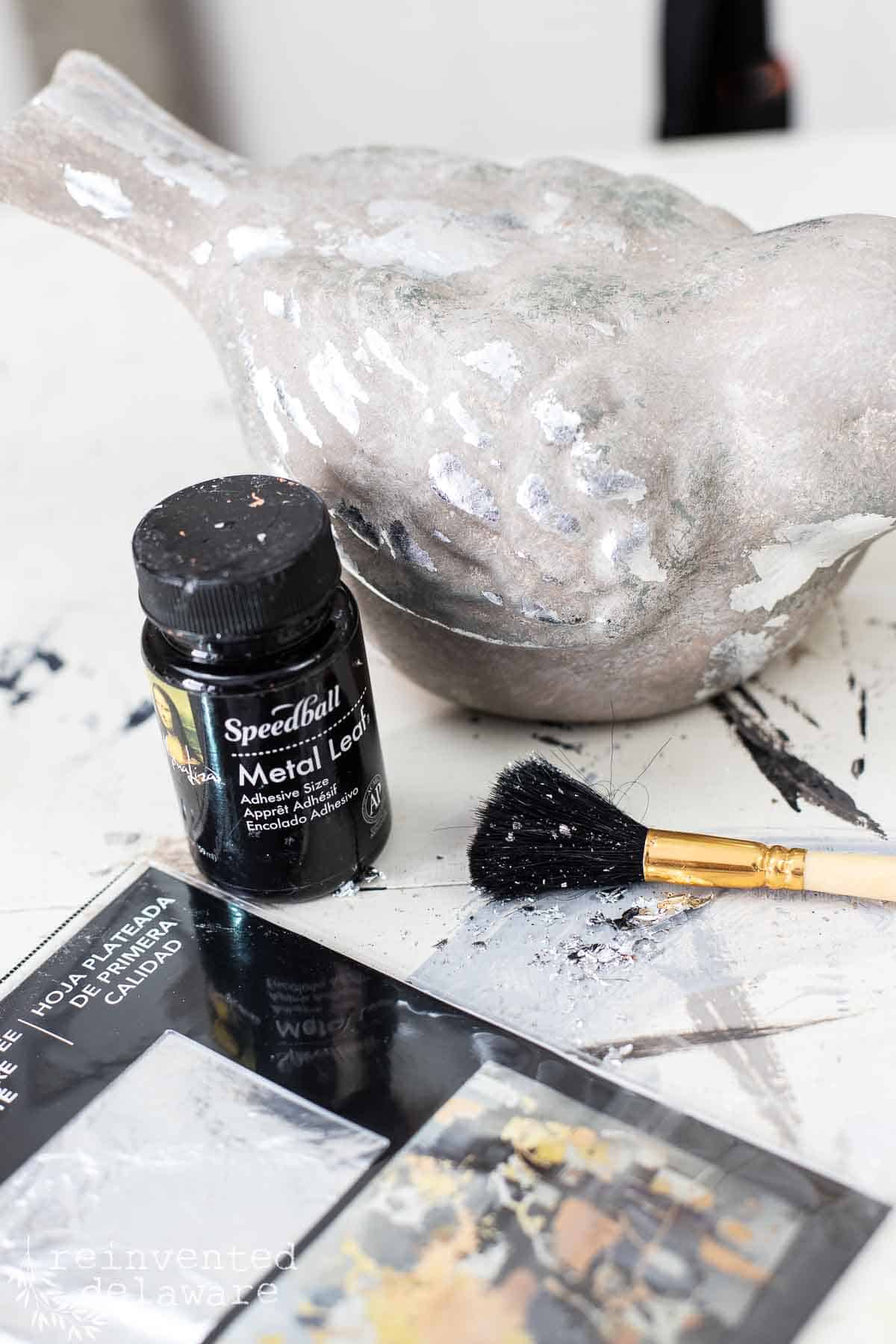 ceramic bird painted to look like cement and then silver leaf added for texture using meal leaf adhesive