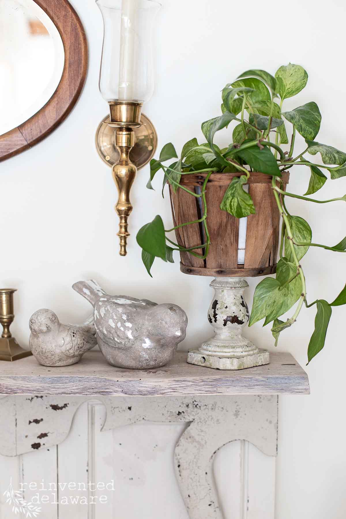faux fireplace mantle with thrift store decor styled together showing a basket planter pot and ceramic birds