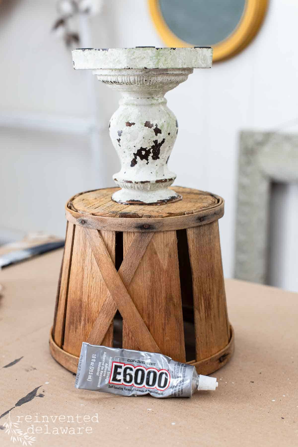 thrift store candlestick being glued to a vintage berry basket with E6000 for spring home decor idea