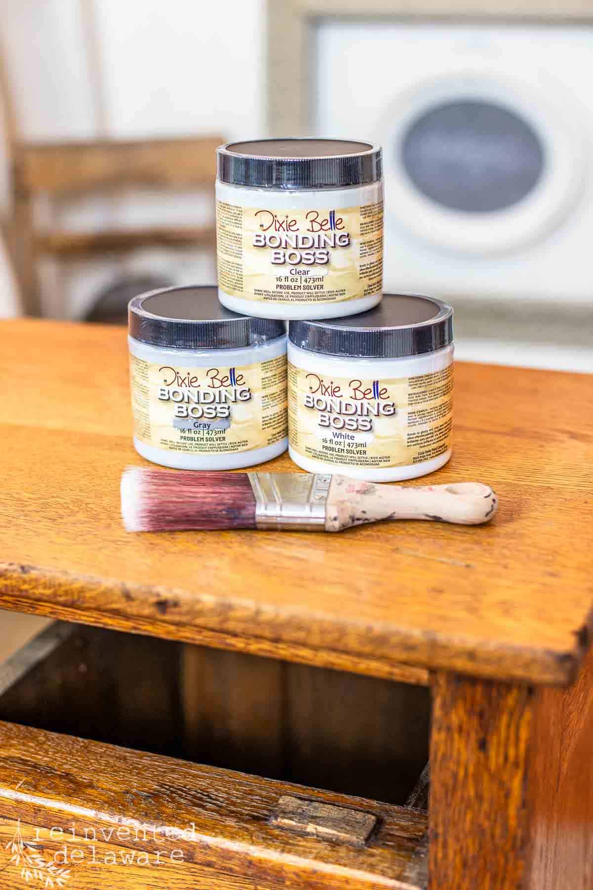 stack of furniture primer in white, gray and clear along with a paintbrush