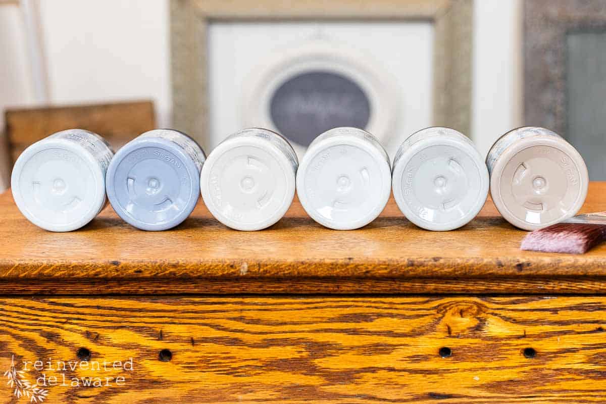 chalk paint jars laying on there side to show off the colors of grey that Silk chalk paint comes in