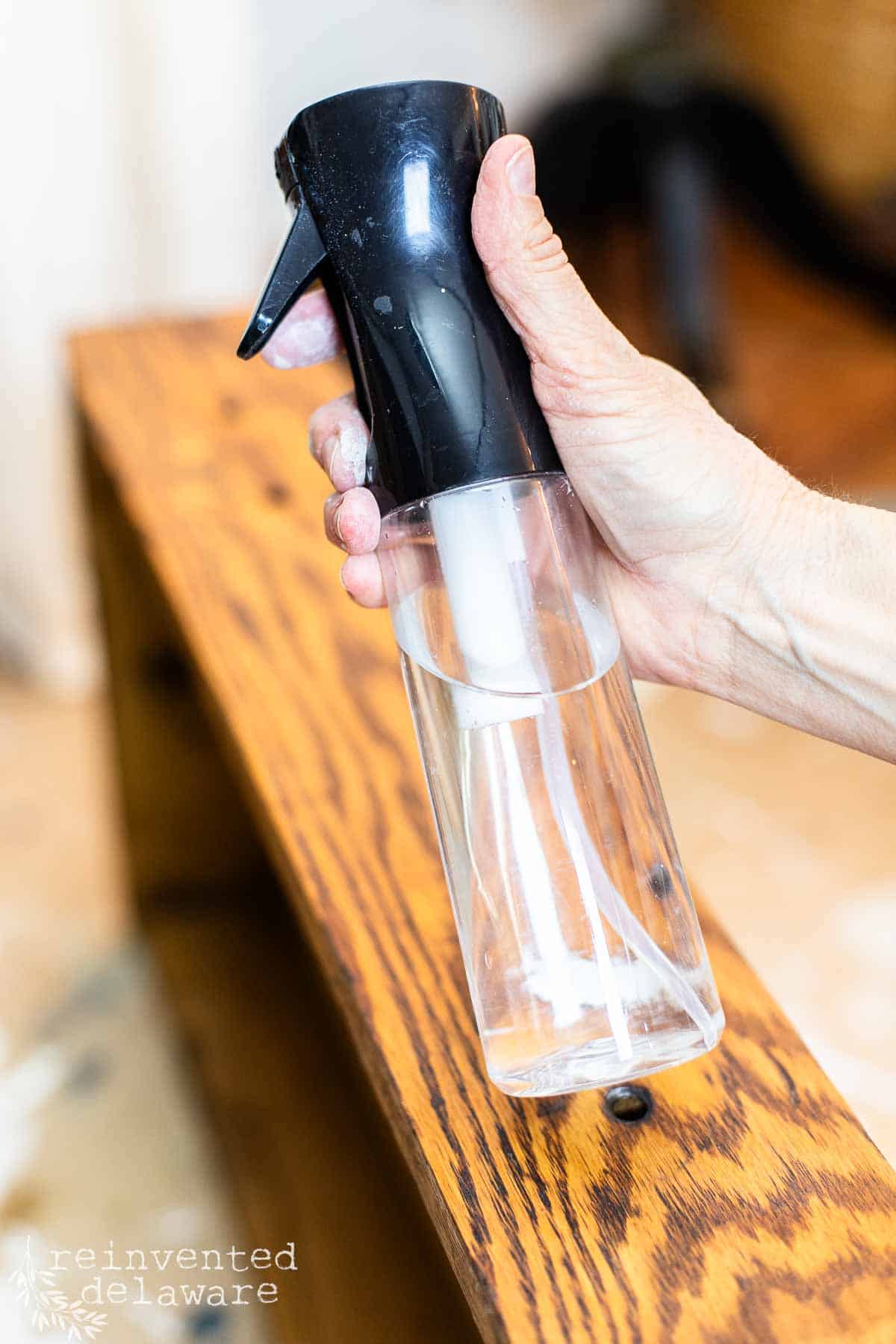 lady holding a mist water spray bottle used for furniture makeovers.