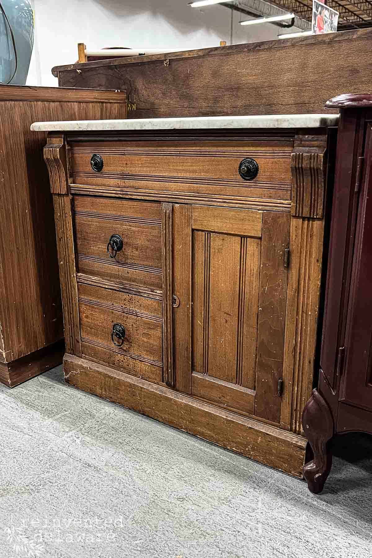 a wood antique washstand with a marble top in a Restore